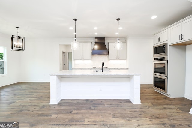 459 Banff Dr, Winder, GA 30680 - kitchen with custom exhaust hood, appliances with stainless steel finishes, tasteful backsplash, ornamental molding, and an island with sink