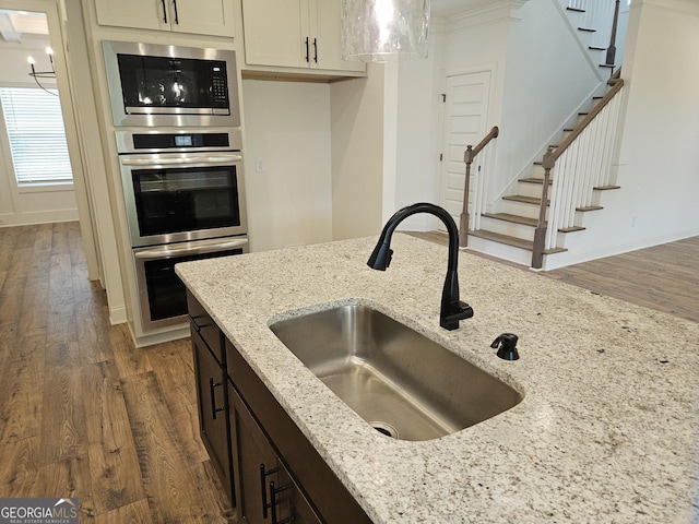 kitchen with light stone counters, dark wood-type flooring, stainless steel appliances, and a sink