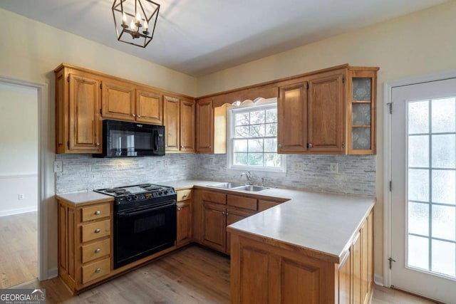 kitchen featuring light countertops, a sink, a peninsula, and black appliances