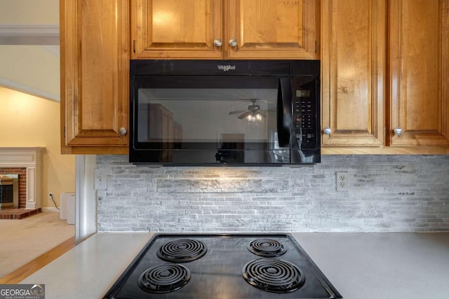 details featuring a brick fireplace, black microwave, light countertops, and decorative backsplash