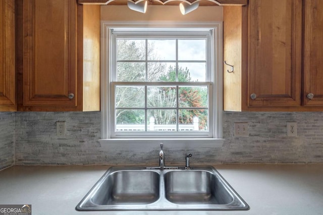 kitchen with tasteful backsplash, brown cabinets, a sink, and light countertops