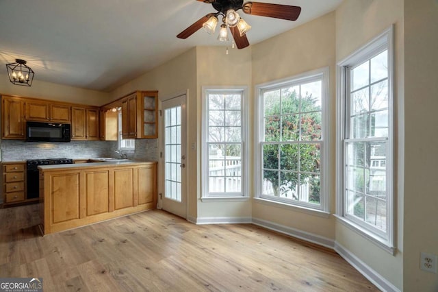 kitchen with tasteful backsplash, light wood-type flooring, baseboards, and black appliances