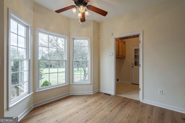 spare room featuring light wood-style floors, ceiling fan, and baseboards