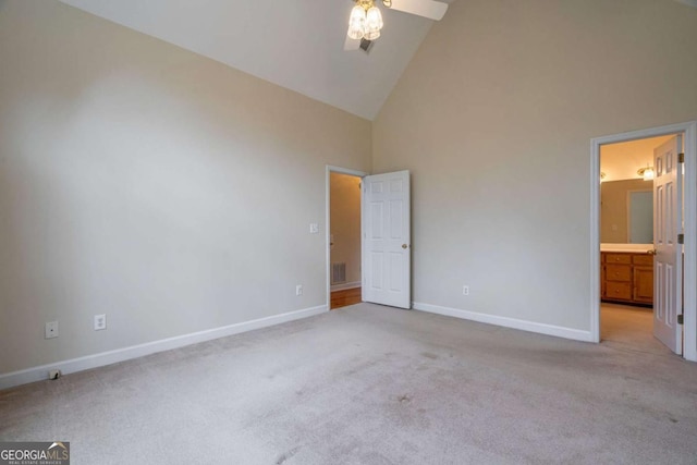 unfurnished bedroom with light colored carpet, visible vents, ensuite bathroom, high vaulted ceiling, and baseboards