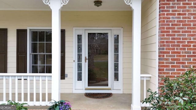 property entrance featuring a porch and brick siding