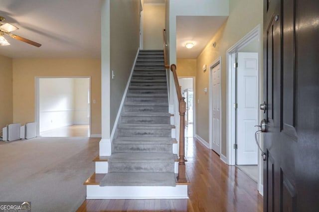 staircase with a ceiling fan, baseboards, and wood finished floors