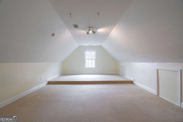 additional living space featuring carpet, visible vents, vaulted ceiling, and baseboards