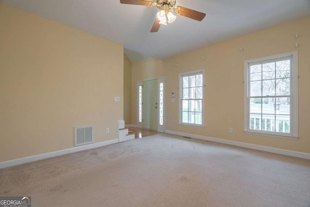 unfurnished room featuring light colored carpet, visible vents, a ceiling fan, vaulted ceiling, and baseboards