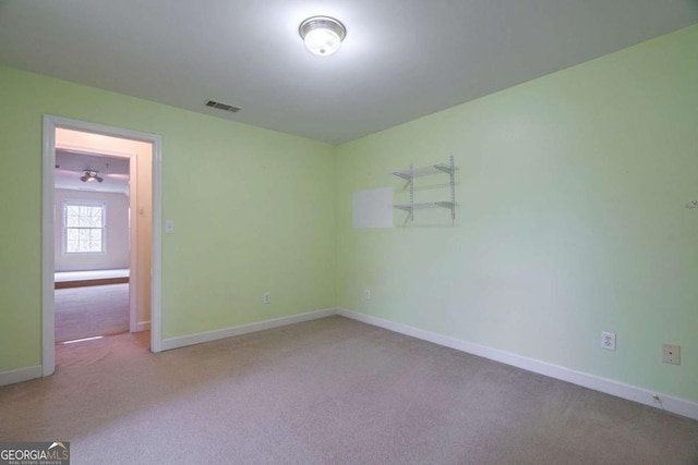 spare room featuring baseboards, visible vents, and carpet flooring