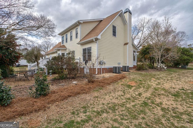 view of property exterior featuring a garage, a patio, a chimney, and cooling unit