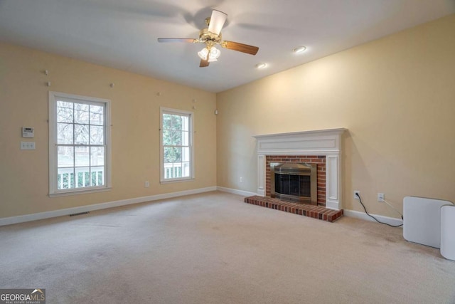 unfurnished living room with baseboards, visible vents, ceiling fan, carpet floors, and a brick fireplace