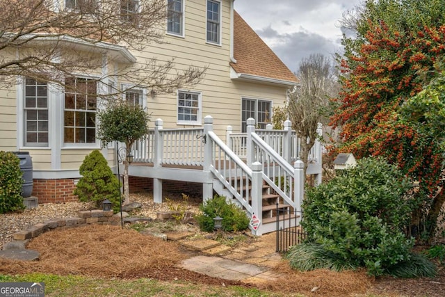 rear view of property with a shingled roof, stairway, and a deck