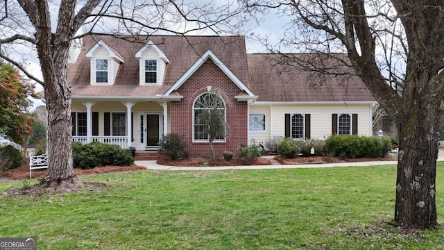 cape cod house with a front lawn, a porch, brick siding, and a shingled roof