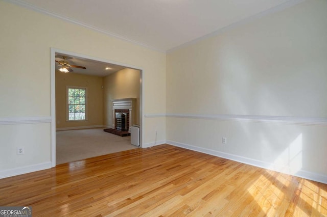 unfurnished living room with ornamental molding, a fireplace, wood finished floors, and baseboards