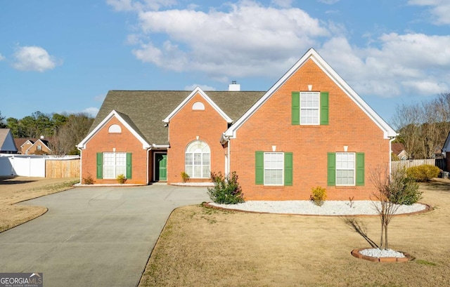 traditional-style house featuring brick siding, a chimney, and fence