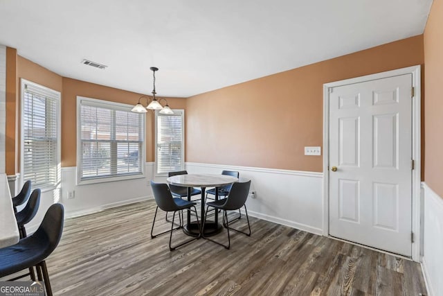 dining space with dark wood-style floors, visible vents, and a healthy amount of sunlight