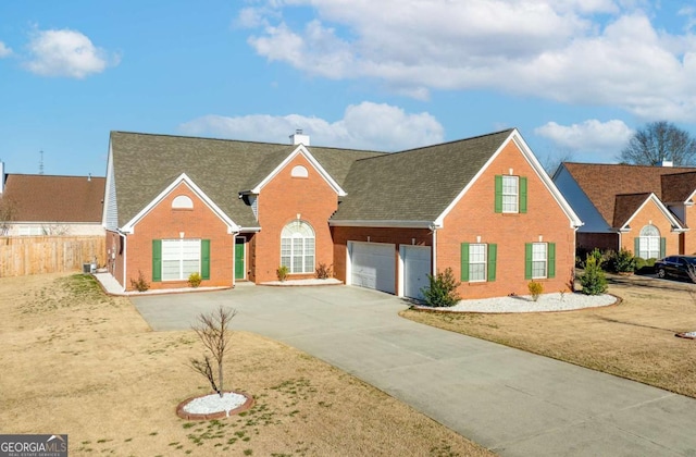 traditional home with brick siding, a chimney, driveway, and fence