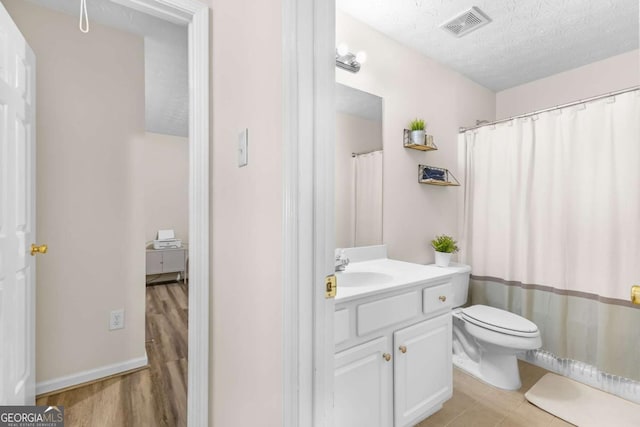 full bath featuring visible vents, toilet, vanity, wood finished floors, and a textured ceiling