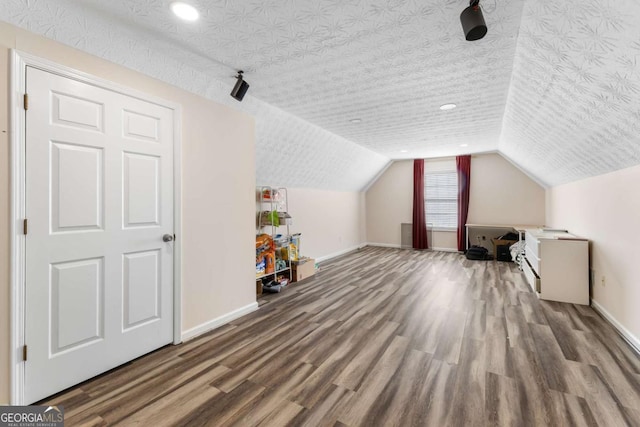 bonus room featuring vaulted ceiling, a textured ceiling, baseboards, and wood finished floors