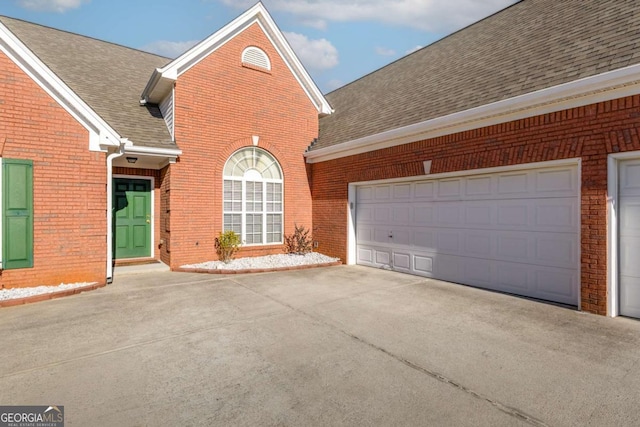 view of front of property featuring brick siding, a garage, and roof with shingles