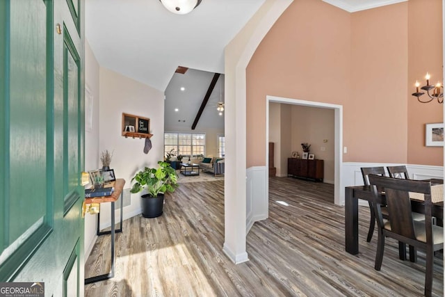 foyer with high vaulted ceiling, wood finished floors, arched walkways, and wainscoting