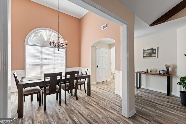 dining area featuring visible vents, arched walkways, an inviting chandelier, and wood finished floors