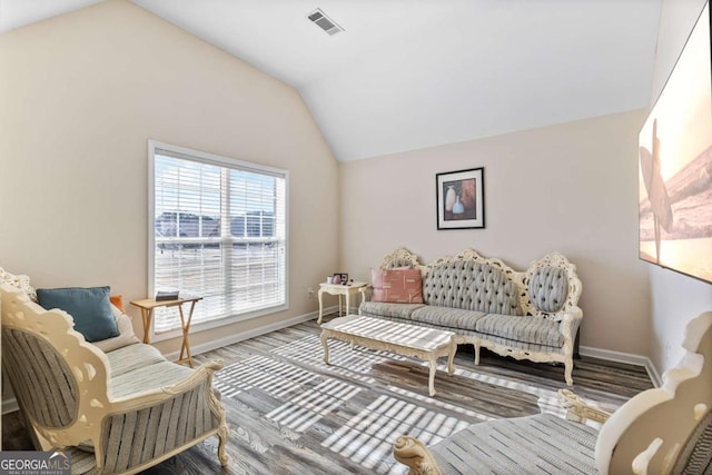 living room featuring lofted ceiling, wood finished floors, baseboards, and visible vents