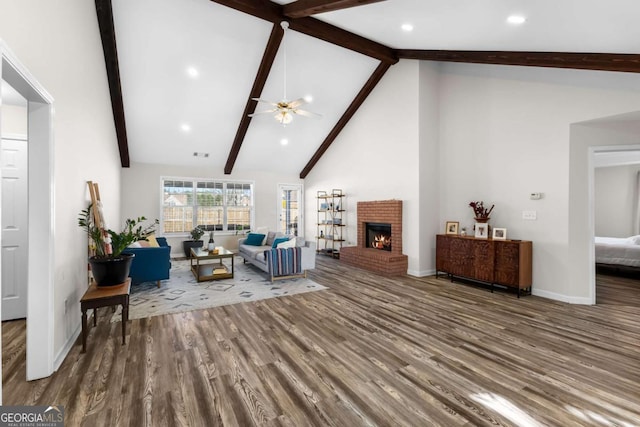 living room with beam ceiling, a fireplace, and wood finished floors