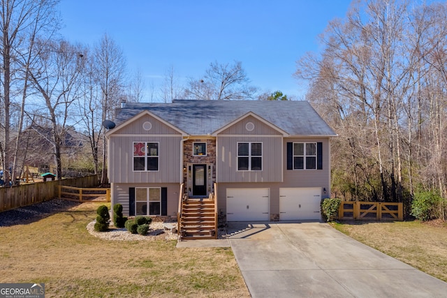 raised ranch featuring a front yard, fence, driveway, and an attached garage