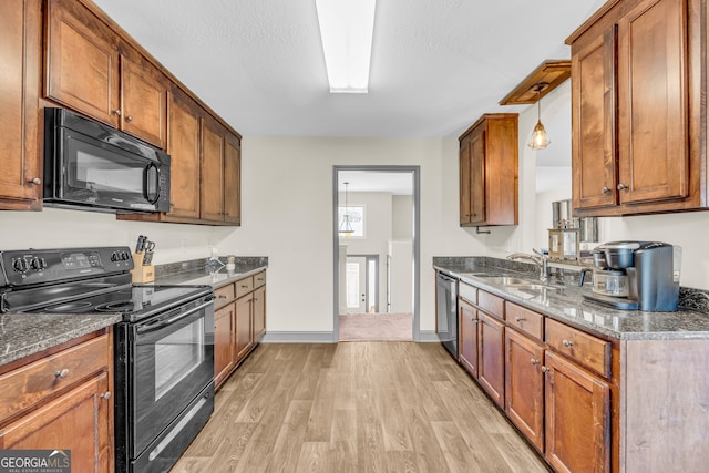 kitchen featuring light wood-type flooring, brown cabinets, a sink, and black appliances