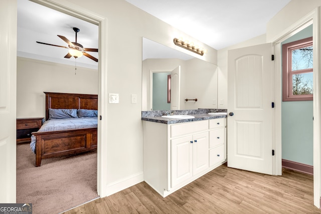 bathroom featuring double vanity, a sink, baseboards, and wood finished floors