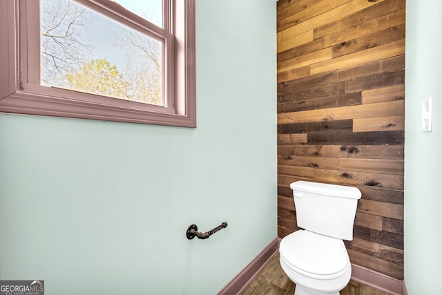 bathroom featuring wood walls, toilet, and baseboards