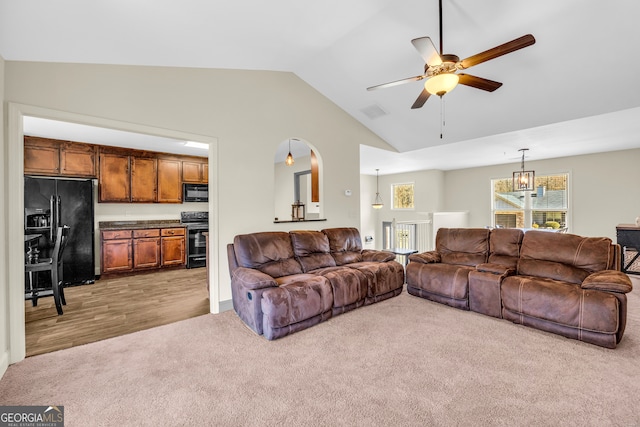 carpeted living room with a ceiling fan, visible vents, and vaulted ceiling