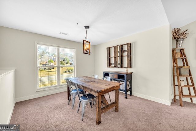 dining space featuring light colored carpet, visible vents, and baseboards