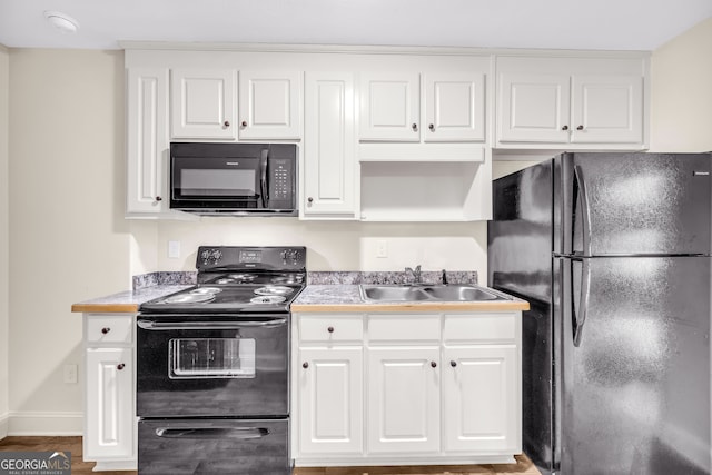 kitchen featuring light countertops, white cabinetry, a sink, and black appliances