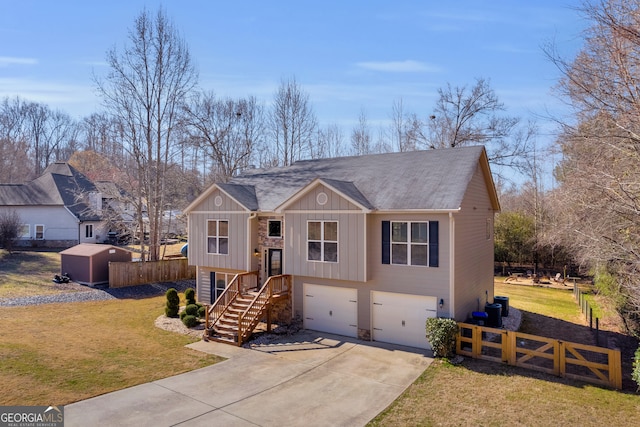 bi-level home with an attached garage, fence, concrete driveway, and a front yard