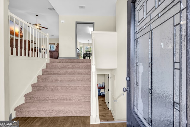 entrance foyer featuring a ceiling fan, visible vents, stairway, and wood finished floors