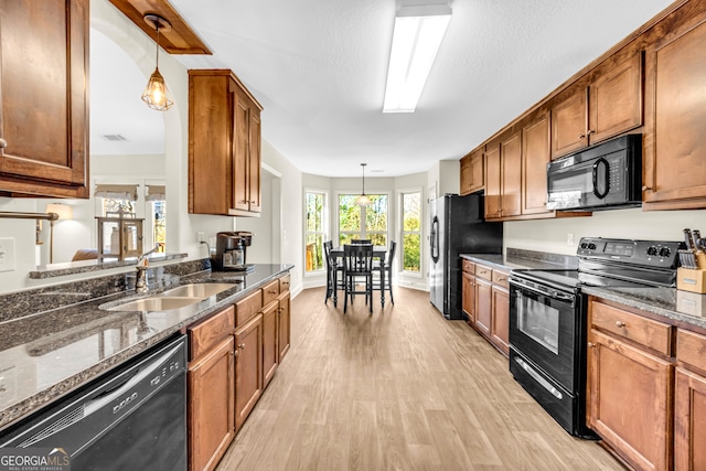 kitchen featuring black appliances, light wood-style floors, a sink, and brown cabinets