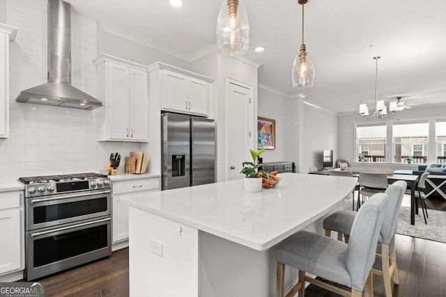 kitchen featuring tasteful backsplash, appliances with stainless steel finishes, ornamental molding, open floor plan, and wall chimney exhaust hood