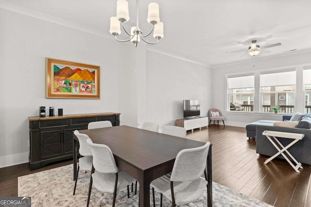 dining area featuring baseboards, dark wood-style flooring, crown molding, and ceiling fan with notable chandelier