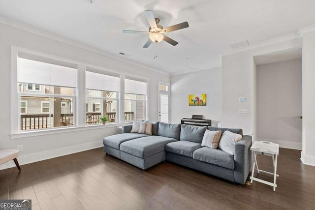 living room featuring dark wood-type flooring, a healthy amount of sunlight, crown molding, and baseboards