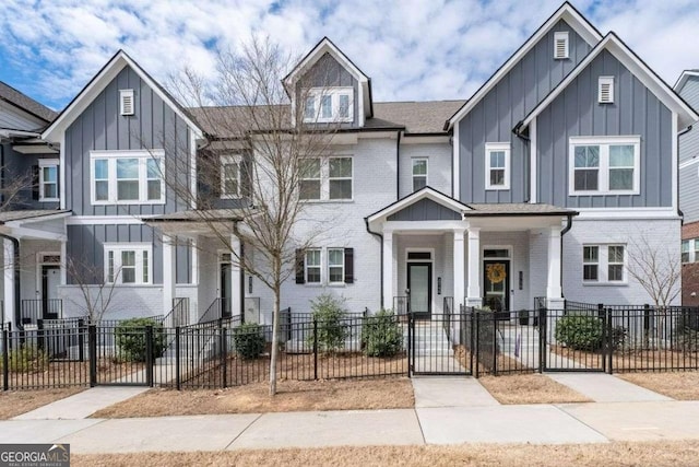 townhome / multi-family property featuring brick siding, board and batten siding, and a fenced front yard