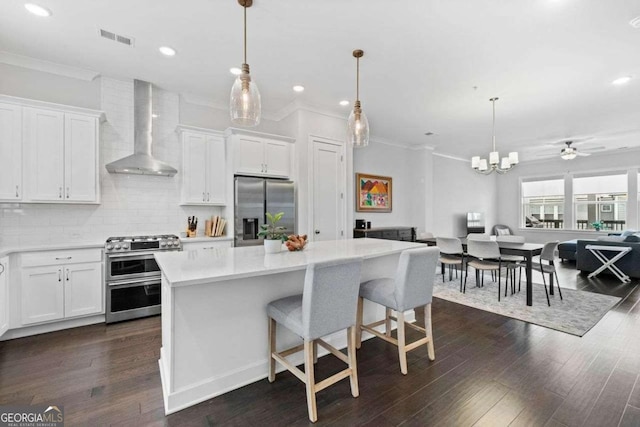 kitchen with open floor plan, light countertops, appliances with stainless steel finishes, backsplash, and wall chimney exhaust hood