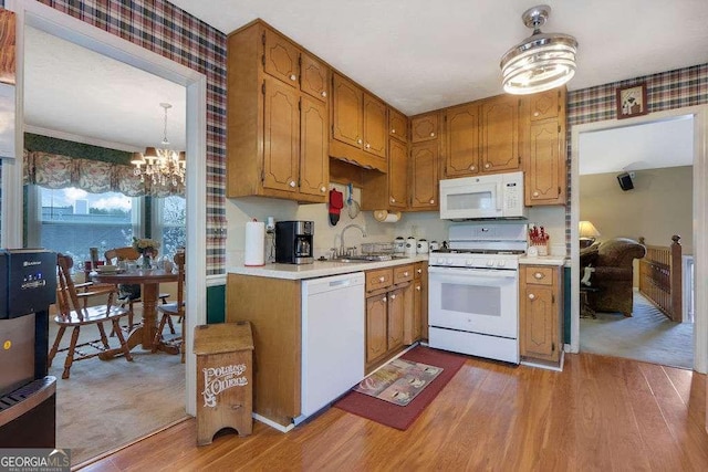 kitchen featuring white appliances, light wood-style flooring, light countertops, and a sink