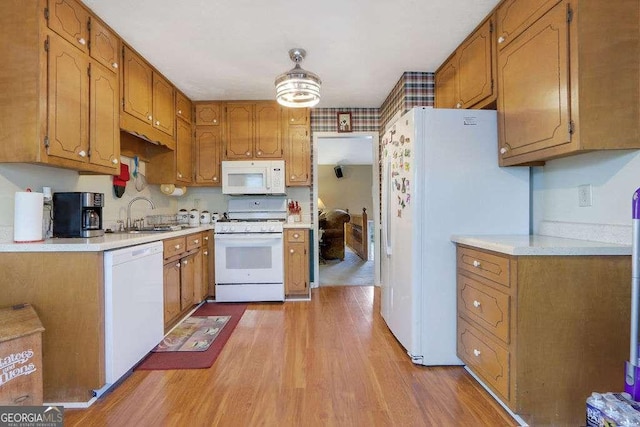 kitchen featuring light countertops, white appliances, a sink, and light wood-style floors