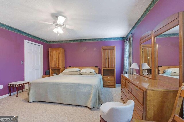 bedroom with a closet, light colored carpet, ceiling fan, and baseboards