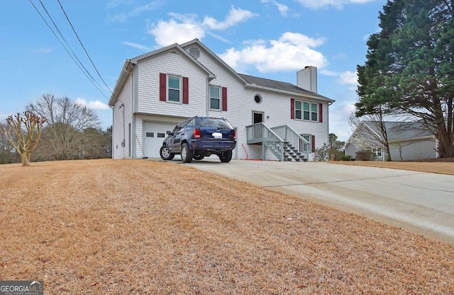 split foyer home with a garage, a chimney, and concrete driveway