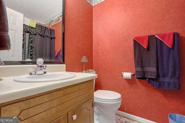 bathroom with toilet, curtained shower, a textured ceiling, and vanity