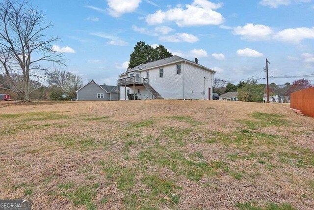 rear view of property featuring stairway, a wooden deck, and a lawn