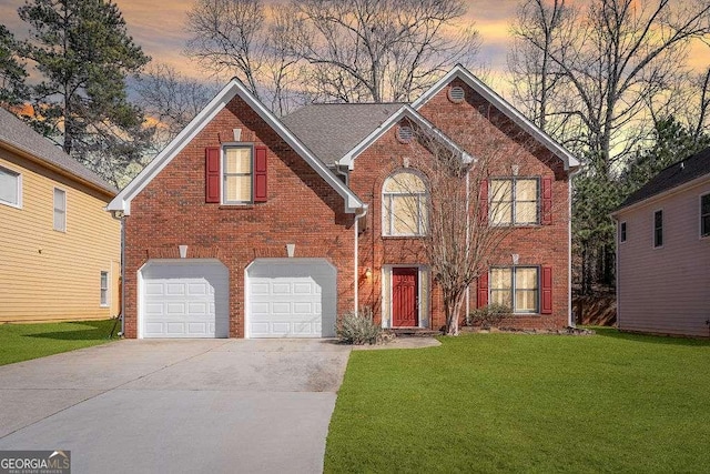 view of front of property with an attached garage, a yard, brick siding, and concrete driveway